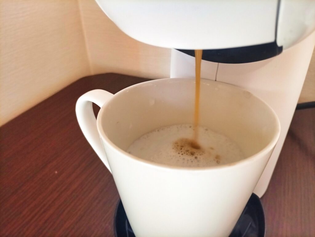 ジェニオ エス ベーシックでキャラメルマキアートのミルクへコーヒーを注いでいる様子