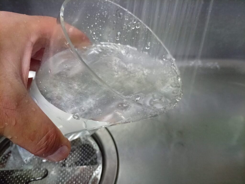 ドルチェグストの給水タンクに水を流し入れて内側をすすぐ様子