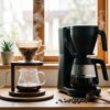 ハンドドリップとコーヒーメーカーが並ぶ温かいキッチンカウンター、朝の光が差し込む本格的なコーヒータイム