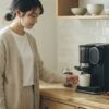 朝のキッチンで電動コーヒーメーカーで挽きたてコーヒーを楽しむ日本人女性