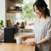 朝のキッチンで電動コーヒーメーカーを使う日本人女性の風景