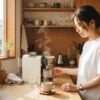 朝のキッチンで電動コーヒーメーカーを使う女性